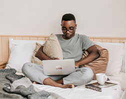 man in bed using laptop